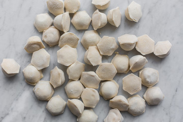Raw frozen pastry dumplings close up over white rustic stone background