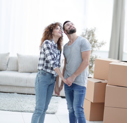 Young couple standing in new apartment and looking up