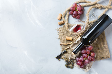 Bottle, corkscrew, glass of red wine, grapes on a table