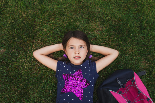 School aged laying in the grass looking up at the sky