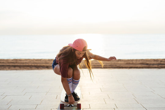 Teen girl riding longboard by beach