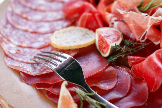 Italian antipasti and appetizers. board with slices prosciutto, salami, dried pork, salami ham with herbs.