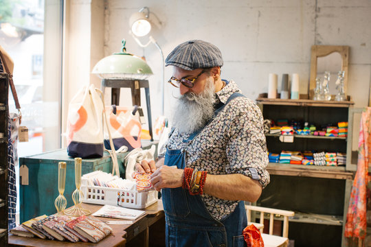 Fashionable Elderly Hipster With Grey Beard Looking at Artisan Notebook