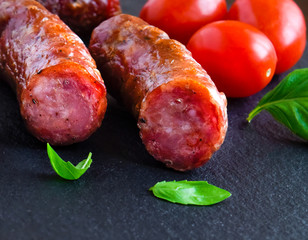 Grilled smoked sausage with herbs and vegetableon a dark background
