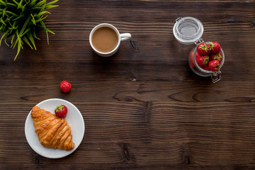 Light summer lunch. Coffee, strawberry, croissant on wooden background top view copyspace