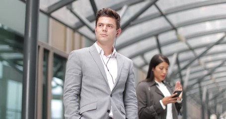 Businessman listening to podcast waiting for train at station