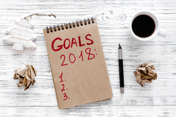 Make a goals list for 2018. Notebook near pen and cup of coffee on grey wooden background top view   