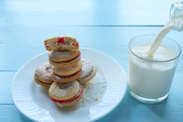 pile of cookies on white plate and pouring milk