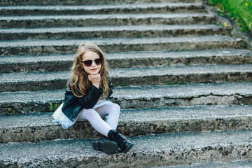 Obraz premium Up view of a happy little girl on the steps pointing at a camera