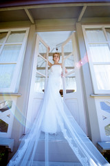 Fototapeta premium Beauty bride in bridal gown with lace veil in the nature