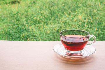 A cup of tea on the wooden table, tea bag in glass, nature background. Free space for text