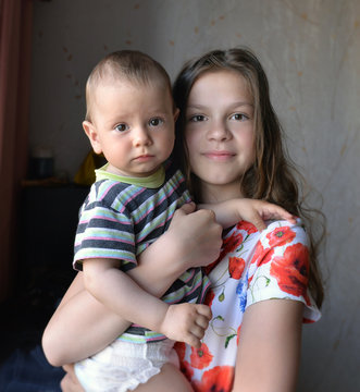 Elder sister holds  small brother in her arms
