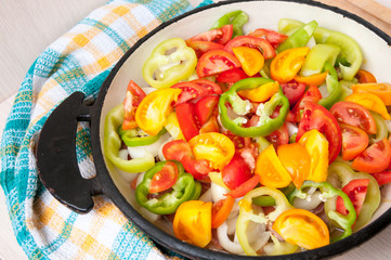 Sliced vegetables in a frying pan stand on table