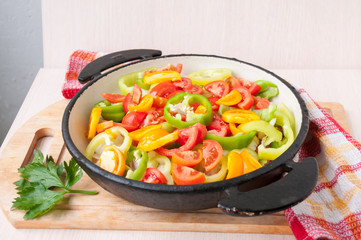 Sliced vegetables in a frying pan stand on table