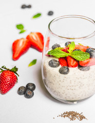 Breakfast yoghurt with chia seeds, forest fruit, blueberry, strawberry, and mint against white background. Healthy lifestyle and eating concept. Superfood.