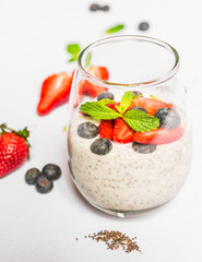 Breakfast yoghurt with chia seeds, forest fruit, blueberry, strawberry, and mint against white background. Healthy lifestyle and eating concept. Superfood.