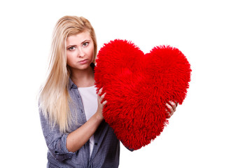 Sad girl holding big red pillow in heart shape