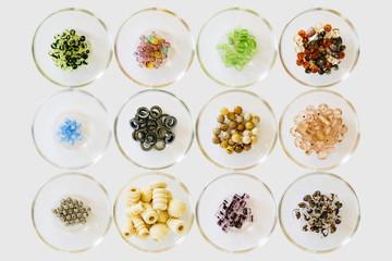 Many different types and colors of beads separated and displayed in several simple glass bowls