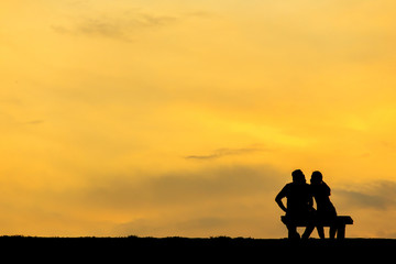 Back view of a couple silhouette sitting on Chair at colorful sunset on background