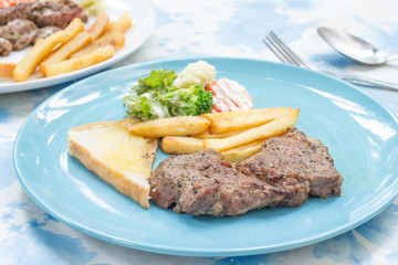 Grilled steak with french fries and vegetables and toast