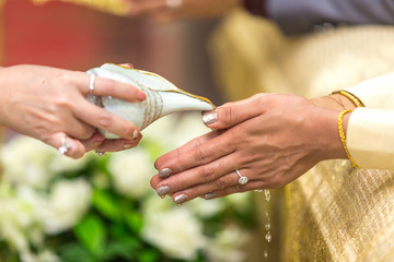 Selective focus with Thai wedding ceremony, water pouring from conch shell to bless the bride.