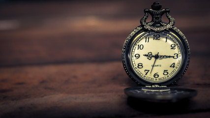 old antique pocket watch showing time on wooden floor with blurred background