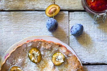 plum pie or tart and plums on rustic background