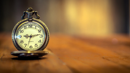 old antique pocket watch showing time on wooden floor with blurred background