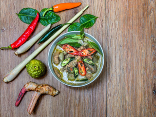 Top view image of Thai food chicken green curry in coconut milk on wooden table.