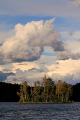 dramatische Wolkenformation und Lichtstimmung am See, Insel mit Bäumen im Herbst, Schweden