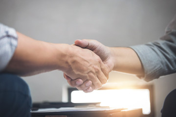 Obraz na płótnie Canvas Two business men shaking hands during a meeting to sign agreement and become a business partner, enterprises, companies, confident, success dealing, contract between their firms
