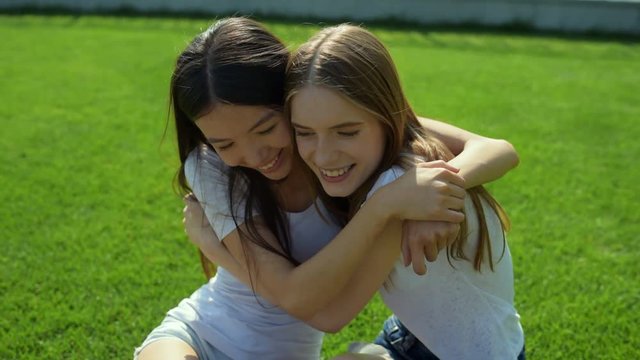 Relaxing positive girls hugging on the grass