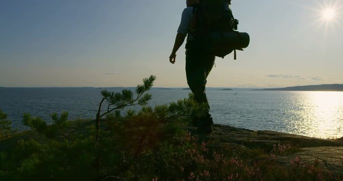 Active man with backpack camping at the moutain by the sea at sunset
