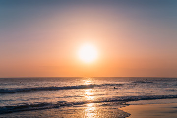 Fototapeta premium Water Sunset Background. Clear Tropical Island View and Sunset Beach Background. Sunset Waves and Amazing Landscape Ocean. Orange Ocean Beach. Sun rays in a Colorful Sunset Background. Beautiful Sky