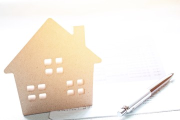 Business, finance, savings, property ladder or mortgage loan concept : Wood house model and pen on saving account passbook  or financial statement