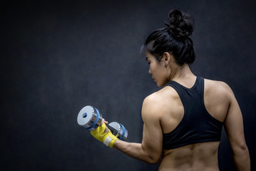 Young Asian woman lifting dumbbell in weight training fitness gym, sport exercise and muscular...