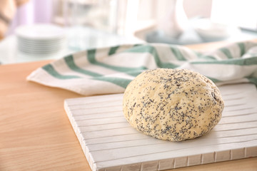Raw dough with poppy seeds on wooden board