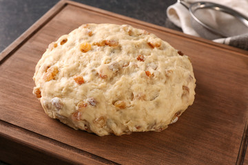 Raw dough with raisins on wooden board