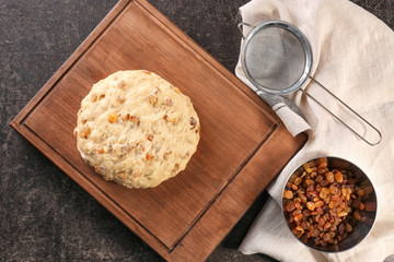 Raw dough with raisins on wooden board