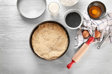 Baking form with raw dough and ingredients on kitchen table