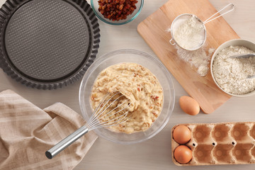 Bowl with raw dough and ingredients on kitchen table