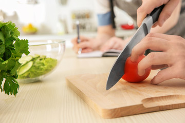 Chef teaching how to slice tomato on cutting board. Concept of cooking classes
