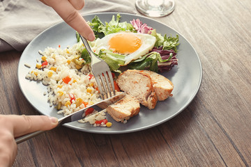 Woman eating delicious rice with meat, egg and mixed salad