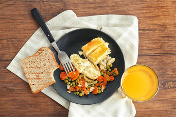 Plate with casserole, vegetables and glass of fresh juice on table