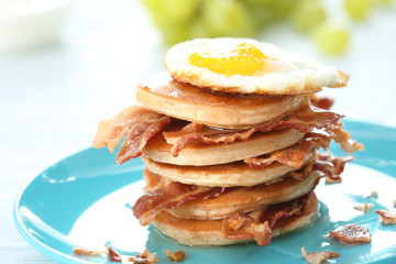 Tasty breakfast with fried egg, pancakes and bacon on table