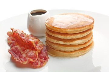 Tasty pancakes and bacon on white background