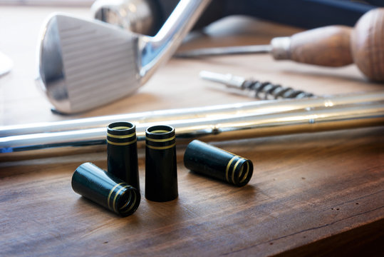 Golf club making or club assembly. Iron club heads and steel shafts with assembly tools on work desk or work bench. Intentionally shot with low key shadows.