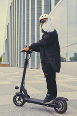 A man vaping and riding by electric scooter.