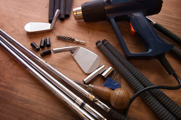 Golf club making or club assembly. Iron club heads and steel shafts with assembly tools on work...