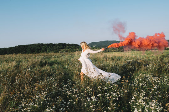 Beautiful bride running with colourful smoke